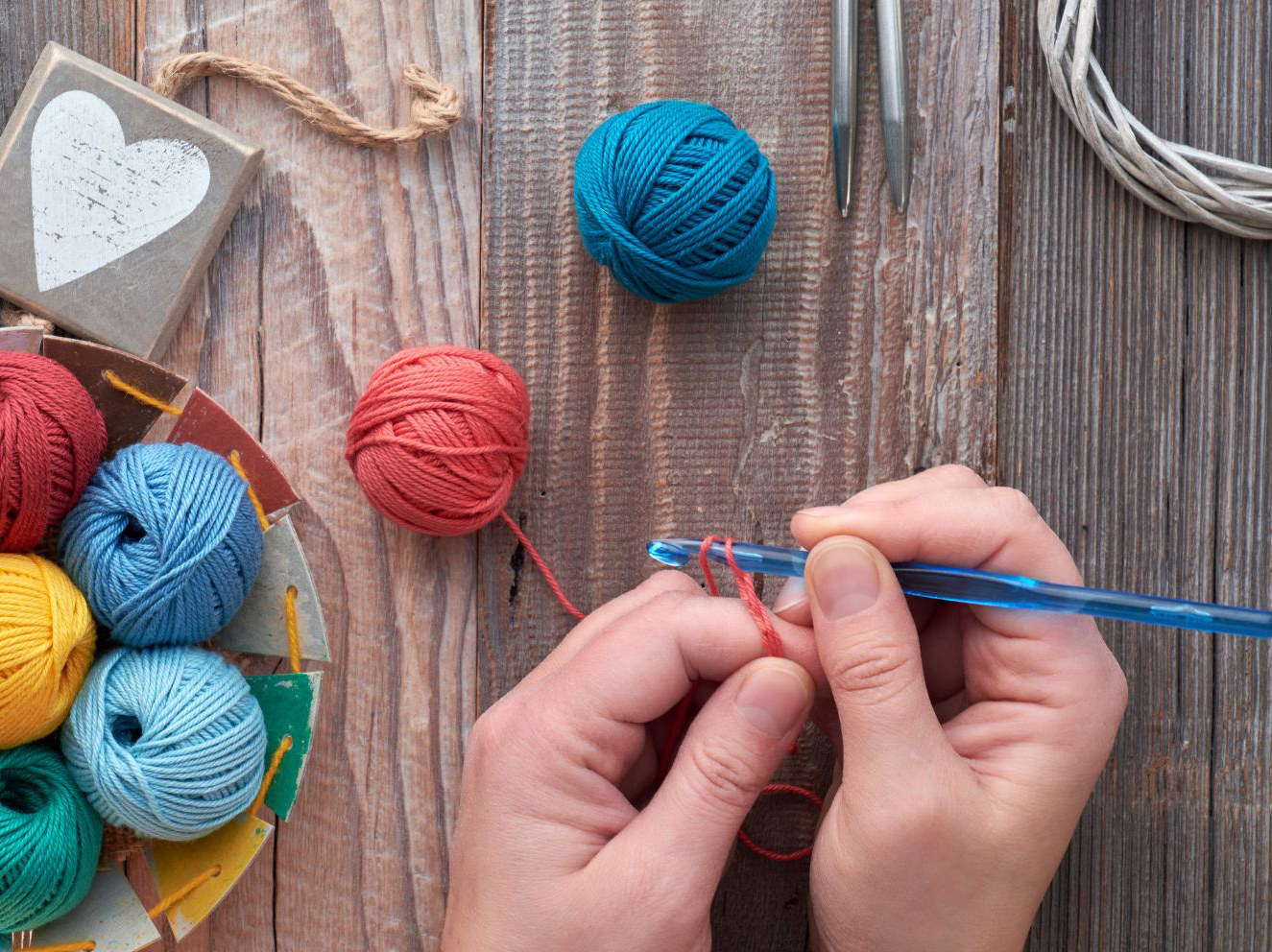 A person is holding a bowl of yarn and a pair of scissors.
