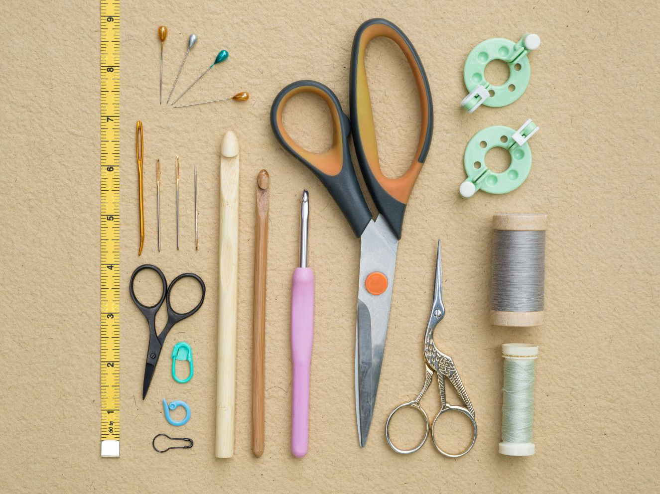 A collection of sewing tools on a beige background.