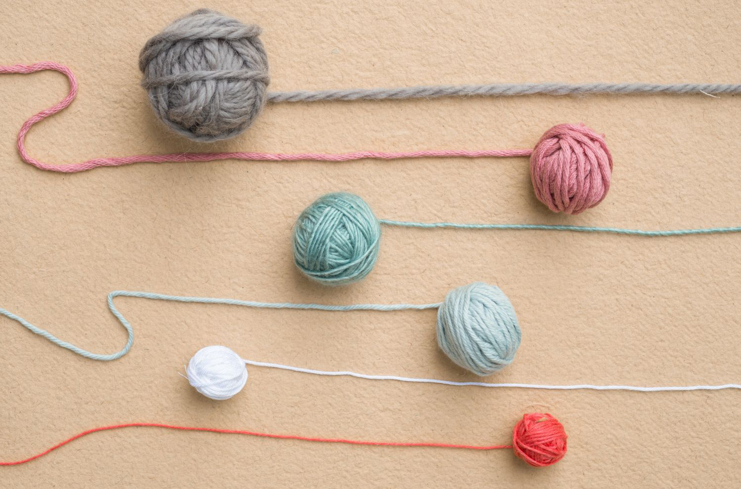 A row of yarn balls on a beige background.