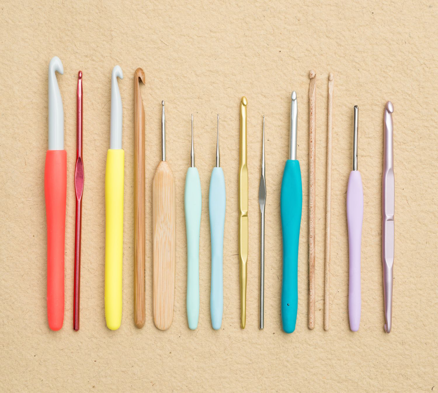 A group of crochet tools on a beige surface.
