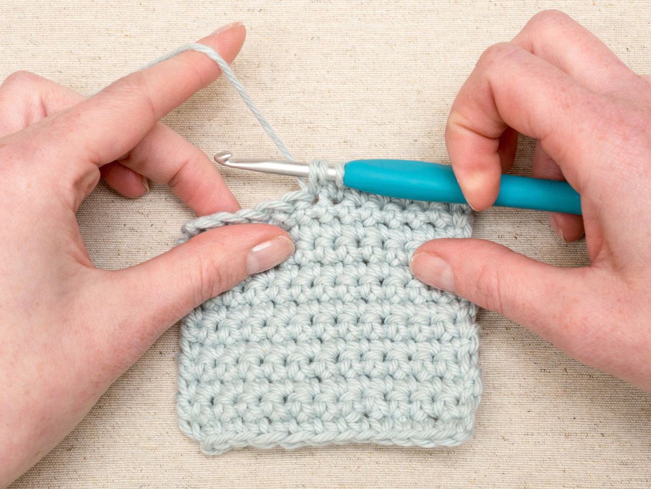 A pair of hands holding a crochet stitch.