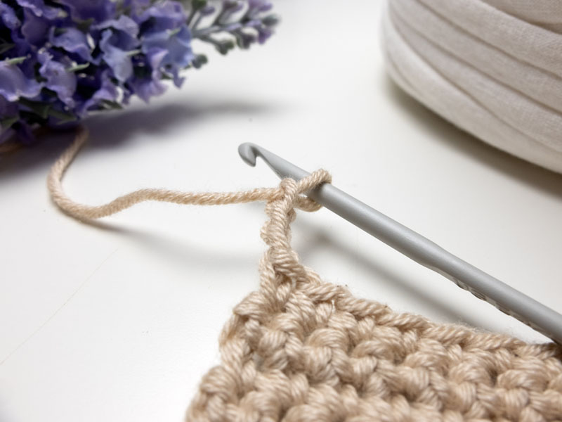 A crocheted piece of fabric with a crochet hook.