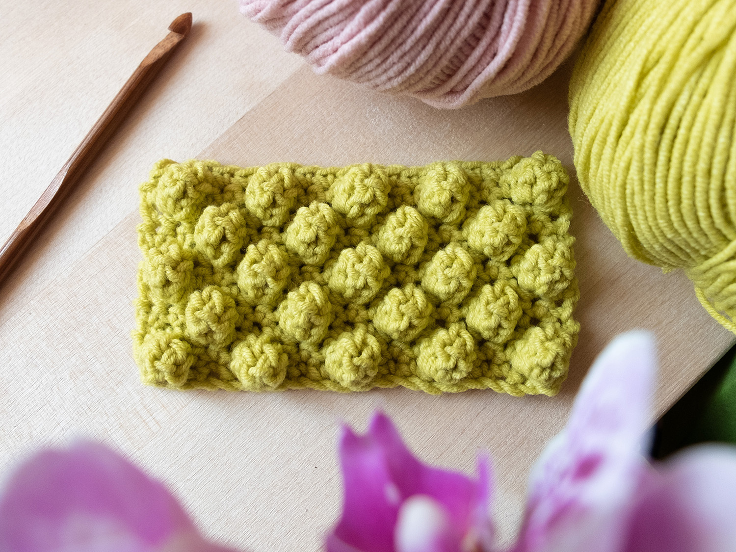 A crocheted square with a flower on it.