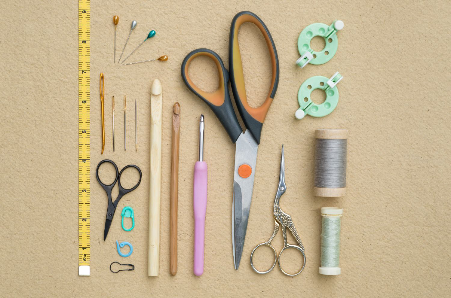 Various sewing tools are laid out on a beige background.