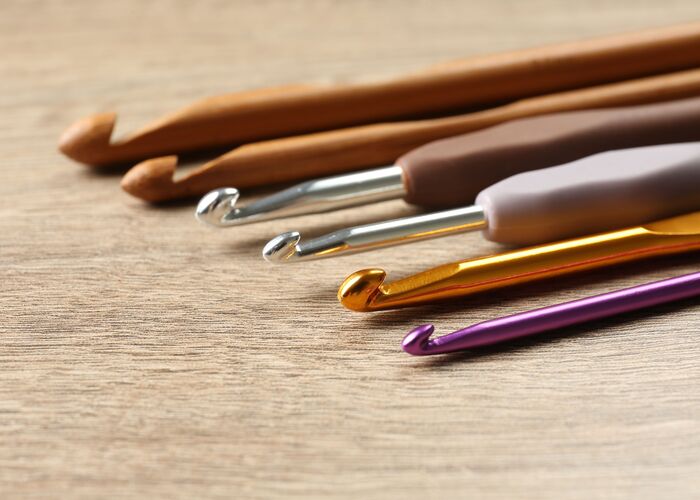 A group of crochet tools on a wooden table.